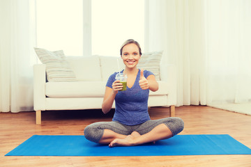 woman with smoothie showing thumbs up at home