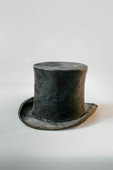 Worn vintage black top hat isolated against white background