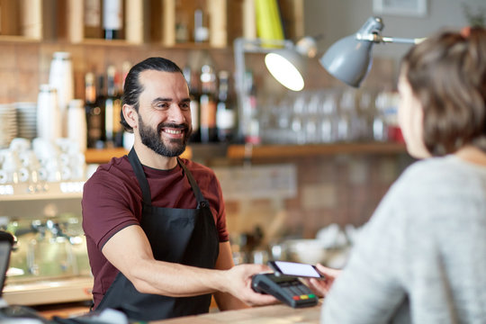 barman and woman with card reader and smartphone