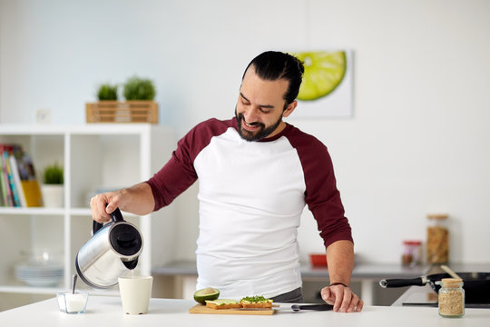 Man With Kettle Making Tea For Breakfast At Home