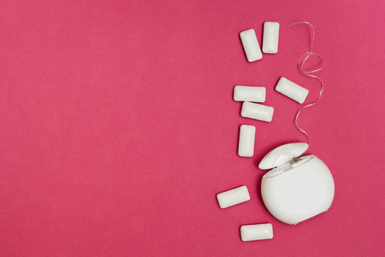 Chewing gum and dental floss on a pink background. Space for text.
