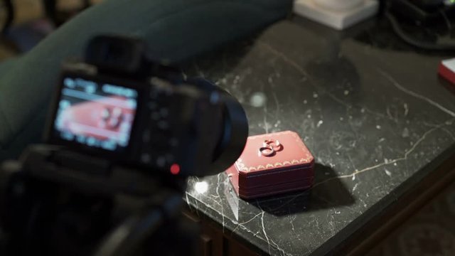 Camera on tripod shooting video of wedding rings indoors