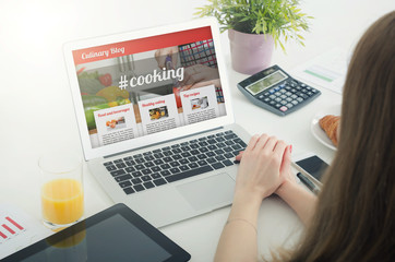 Woman using laptop in home. Culinary website blog concept