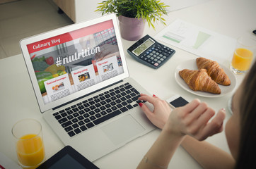 Woman using laptop in home. Culinary website blog concept