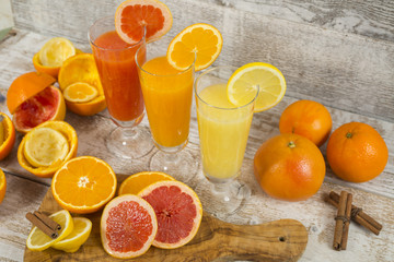 Citrus juices in glass and a slice of  lemon, grapefruit and  orange on wooden background .