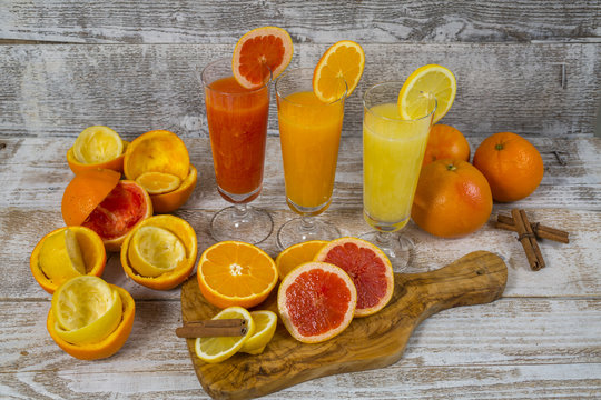 Citrus juices in glass and a slice of  lemon, grapefruit and  orange on wooden background .