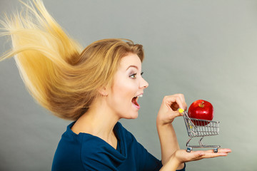 Woman holding shopping cart with apple inside