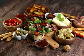 Italian antipasti wine snacks set. Cheese variety, Mediterranean olives, pickles, Prosciutto di Parma, tomatoes, artichokes and wine in glasses