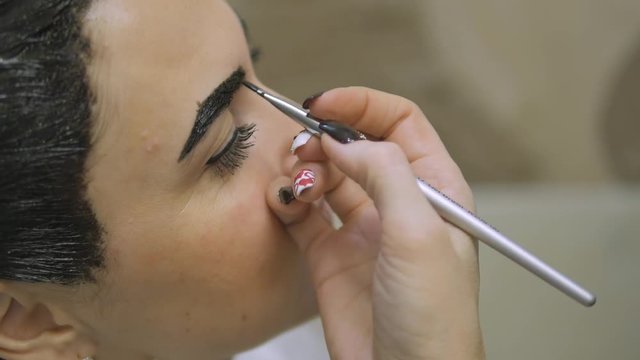 Young woman with hair in the paint, to eyebrow make-up sitting from the master image maker beauty salon ultra HD