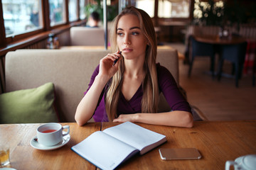 Female writing in notebook in restaurant.