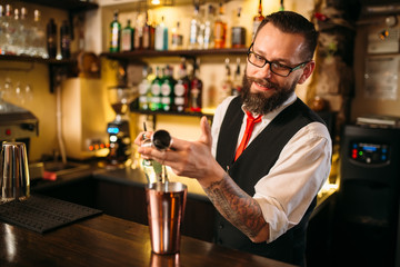Bartender pouring alcohol beverage in metal glass