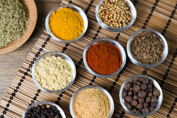 Various fresh spices in bowls, wooden background, 