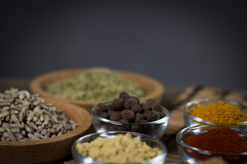 Various spices in bowls with fresh seasoning on rustic wooden background, closeup
