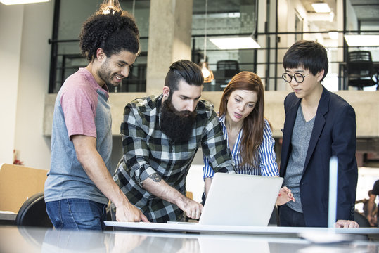 Creative colleagues working together on laptop computer