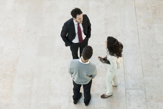 Business manager talking to associates in office lobby