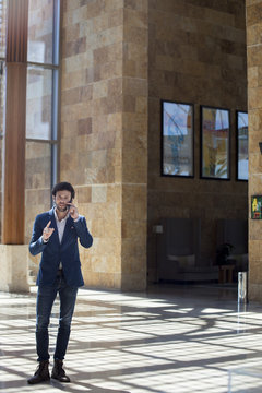 Casually dressed businessman talking on cell phone in lobby