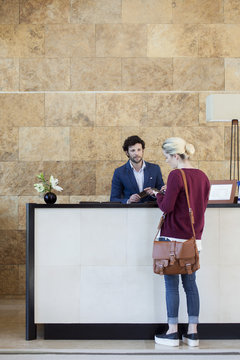 Woman text messaging during transaction with receptionist