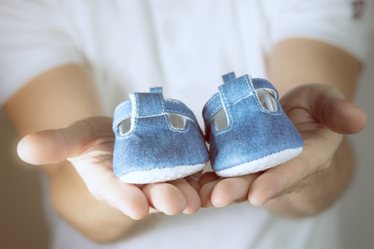 Blaue Babyschuhe in H&auml;nden vom Vater