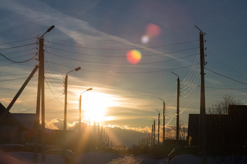 A silhouette of high voltage power lines on colorful sunset background in the city.
