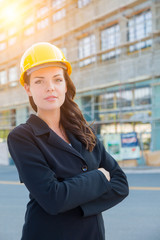 Portrait of Young Attractive Professional Female Contractor Wearing Hard Hat at Construction Site.