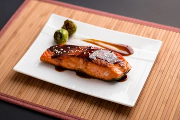  Teriyaki salmon plate on bamboo mat. Japanese cuisine inspired dinner consisting of a grilled salmon fillet glazed in delicious teriyaki sauce (soy sauce base). Healthy brussel sprouts as sides. © lounom