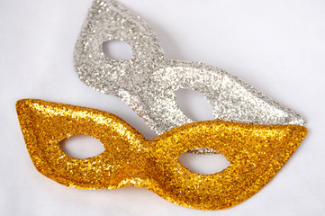 Gold and silver theatrical masks on a light background