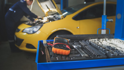 Fototapeta premium Defocused view - mechanic repairs a car - unscrews detail of automobile - garage service