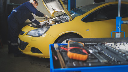 Mechanic repairs a car - unscrews detail of automobile - garage service