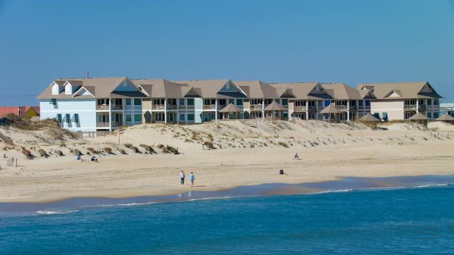 Outer Banks Nags Head NC Beach with Condos and People Walking on Sand alongside Atlantic Ocean Water Waves on an Idyllic Sunny Day in North Carolina