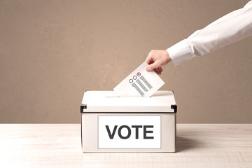 Close up of male hand putting vote into a ballot box