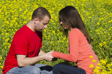 Couple praying in a field of flowers holding hands.