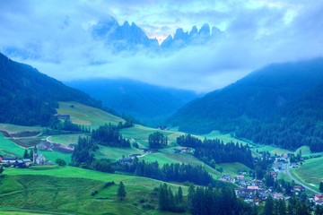 Fototapeta na wymiar Beautiful scenery of majestic Puez Odle or Geisler Mountain Peaks in Val di Funes with view of Santa Maddalena (Magdalena) village in the green grassy valley in Dolomites, South Tyrol, Italy, Europe