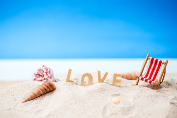 valentine decoration with love wooden text and beach chair on white sand beach with tropical blue sea and clear blue sky,Image For Love Valentine Day or summer   vacation Concept.