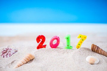 Colorful Candle Number 2 0 1 7 Over Blurred Blue Sea and Sand Beach with Clear Blue Sky ,Image for New Year 2017 Celebration Decorative Concept.