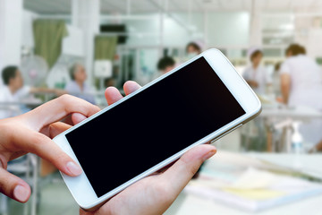 woman hand hold and touch screen smartphone or cellphone over blurred hospital background,vintage tone.