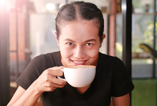 woman holding hot cup of coffee, with heart shape