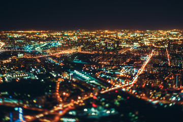 Fototapeta premium True tilt shift shooting of highway, railway and residential district in night metropolis from high point: multiple residential houses in focus in the middle, strong bokeh in background and foreground