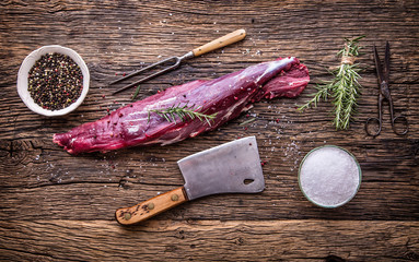 Raw beef meat. Raw beef tenderloin steak on a cutting board with rosemary pepper salt in other...