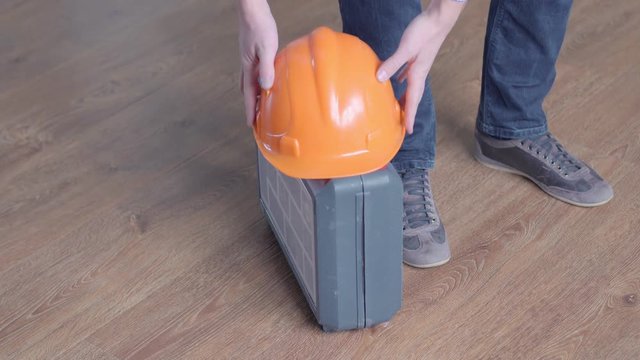 repair, building, construction and people concept - close up of man carrying tool box and leaving it with hardhat
