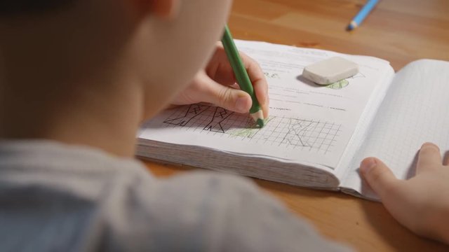 Left-hander child draws in a coloring book - Back view