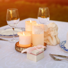 Table decorated with candles and angels for wedding or romantic dinner. Gift box with wedding rings, proposal or marriage concept