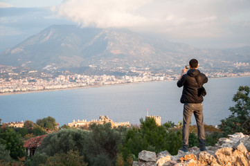 Man tourist taking photos of a city from the high point