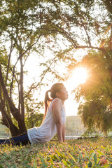 Naklejka premium Young Woman Doing Yoga Meditation and Stretching Exercises in the park