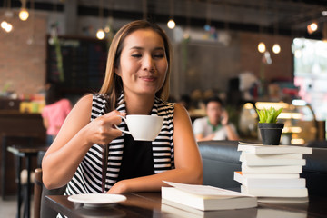 Asian woman relaxing and reading a book in the cafe. Women lifestyle concept.