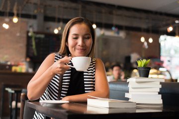 Asian woman relaxing and reading a book in the cafe. Women lifestyle concept.