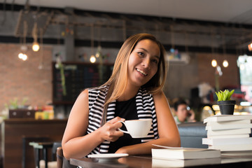 Asian woman relaxing and reading a book in the cafe. Women lifestyle concept.