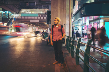 Handsome bearded man standing roadside street while traveling at night in bangkok city thailand.