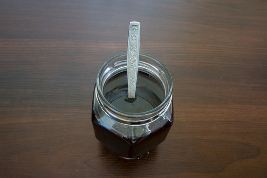 Blackberry jam in a glass jar with a teaspoon.