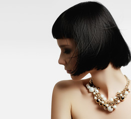 The beautiful woman in expensive pendant close-up. Beautiful young woman model with perfect makeup...