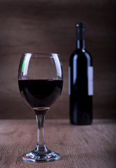 Glass of wine with a bottle on a wooden backgound